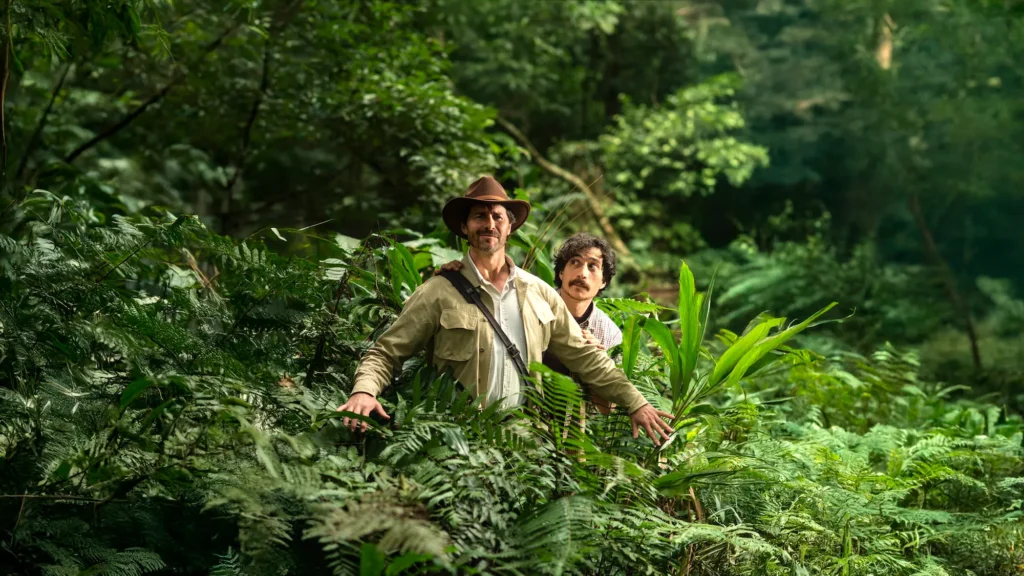 final version of the previous photo of the man looking on carefully at the jungle guide as he leads him through the dense jungle.