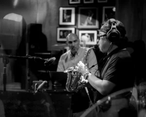 Tran Manh Tuan plays while the producer looks on.